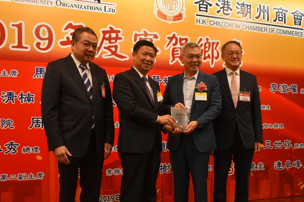 本會會長林宣亮（右一）、香港潮屬社會總會主席陳幼南（左一）與中聯辦社團聯絡部部長李文（左二）致贈賀狀予九龍樂善堂常務總理郭予宏（右二）s