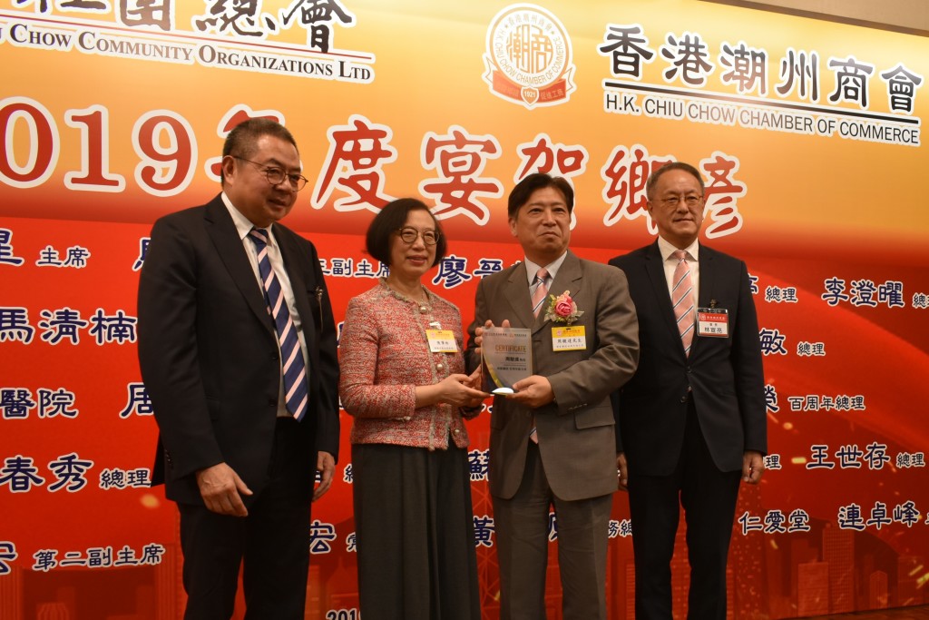 本會會長林宣亮（右一）、香港潮屬社會總會主席陳幼南（左一）與食物及衛生局局長陳肇始（左二）致贈賀狀予會董兼博愛醫院百周年副主席周駿達（右二）s